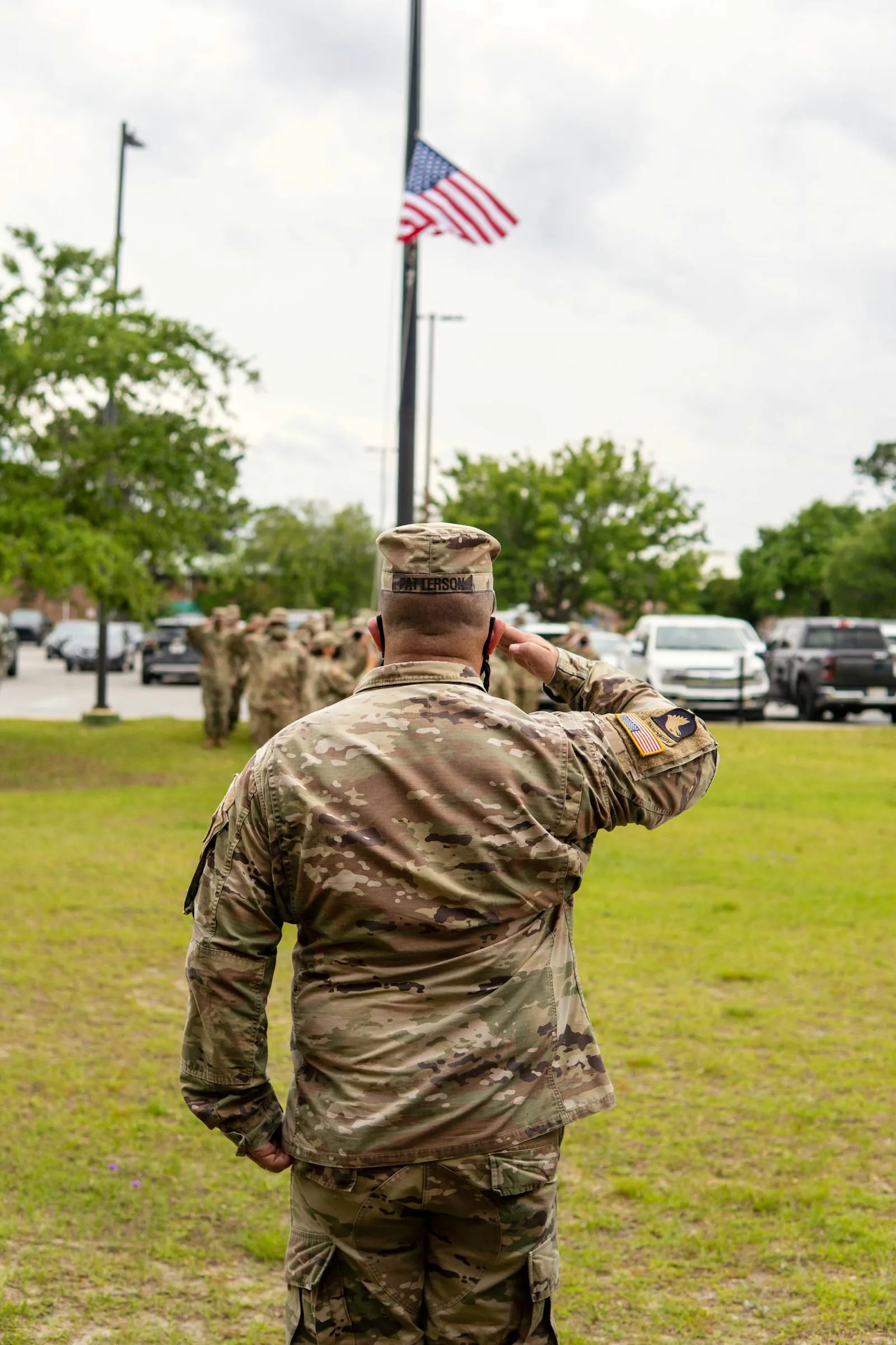 A service member salutes the American flag flying at half-mast during a memorial ceremony
